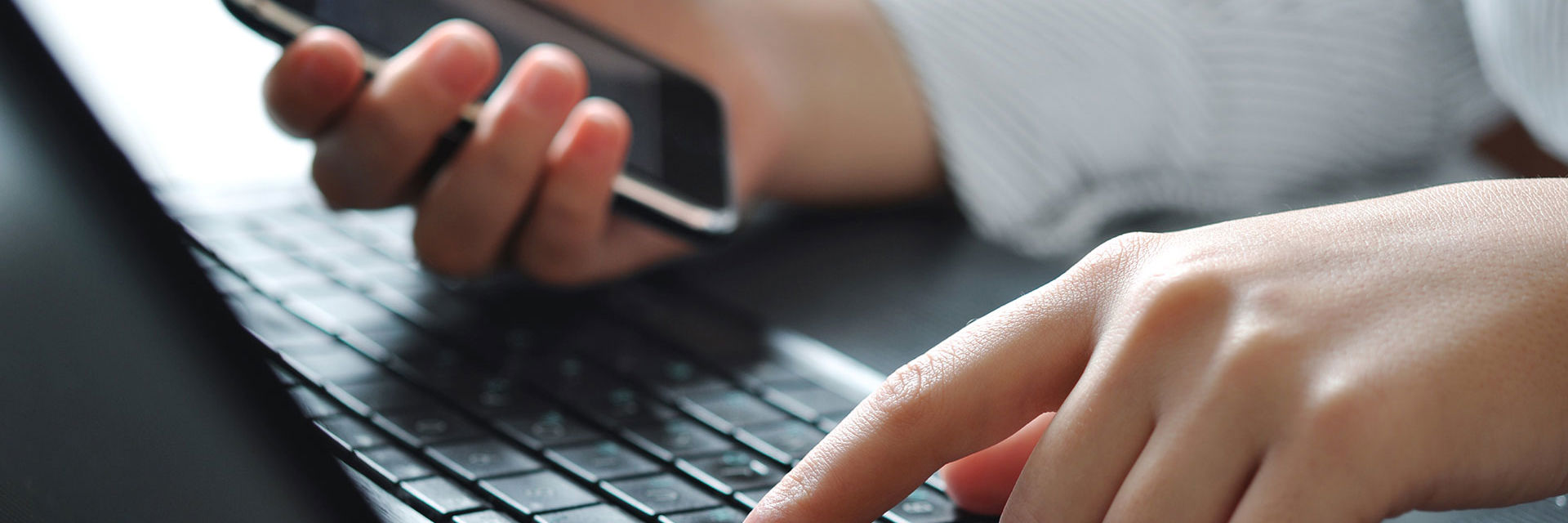Hænder, tastatur og mobiltelefon