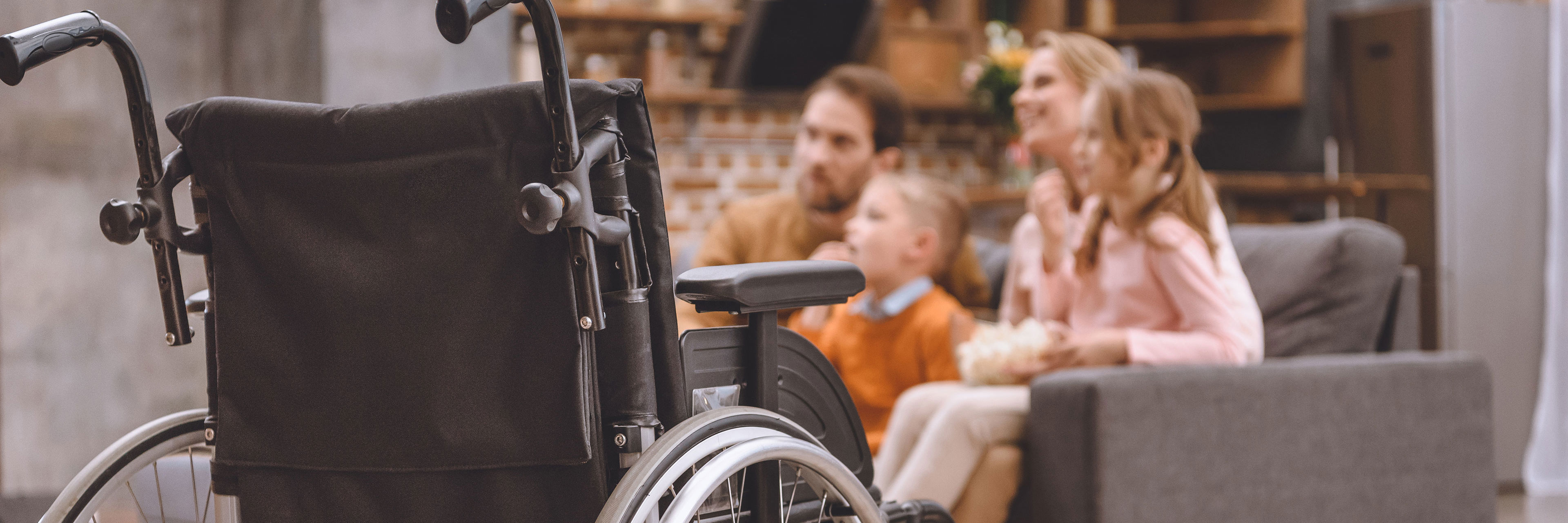 Close up af en kørestol med en familie i baggrunden