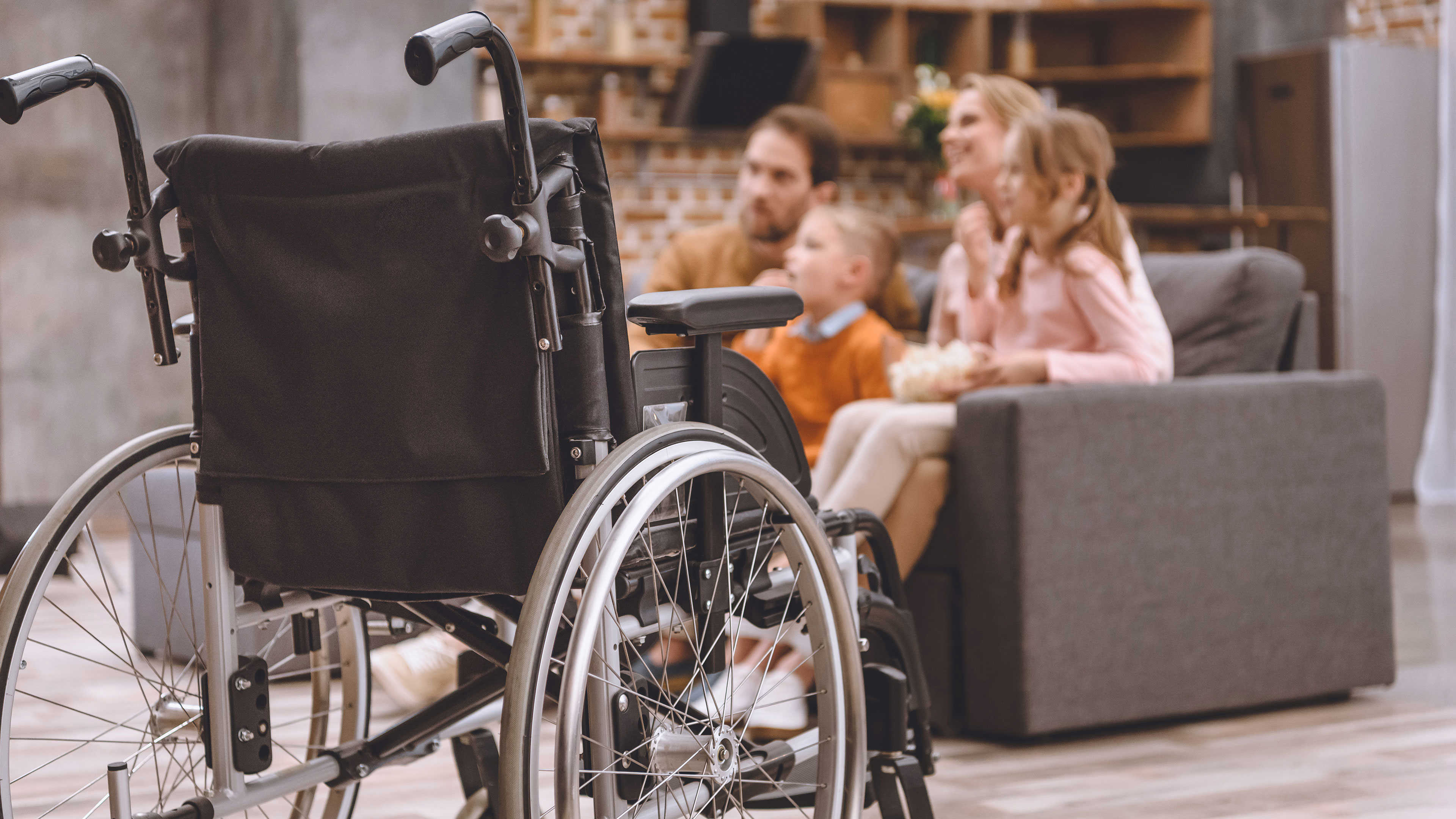 Close up af en kørestol med en familie i baggrunden