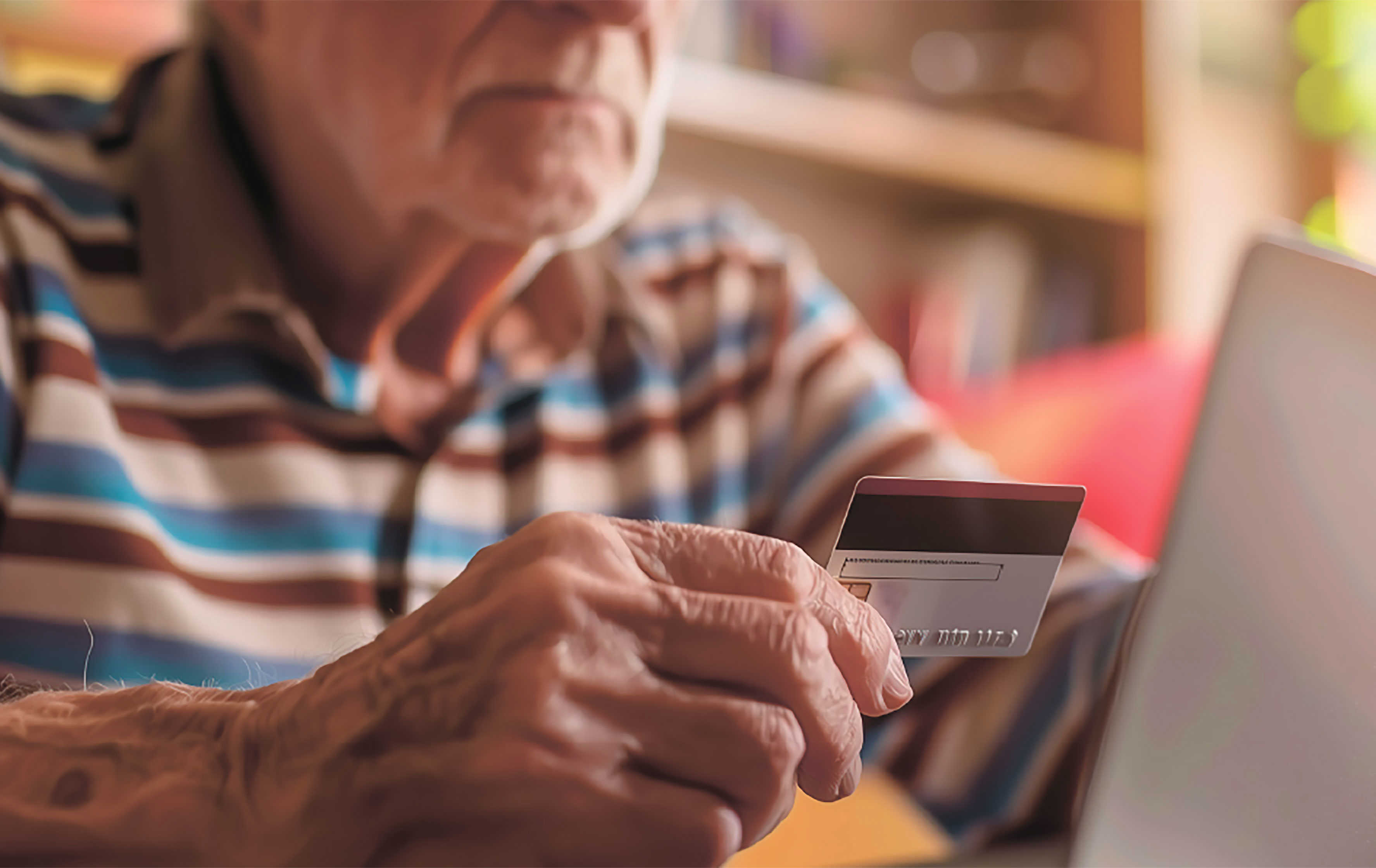 Ældre mand der holder et dankort op foran en PC
