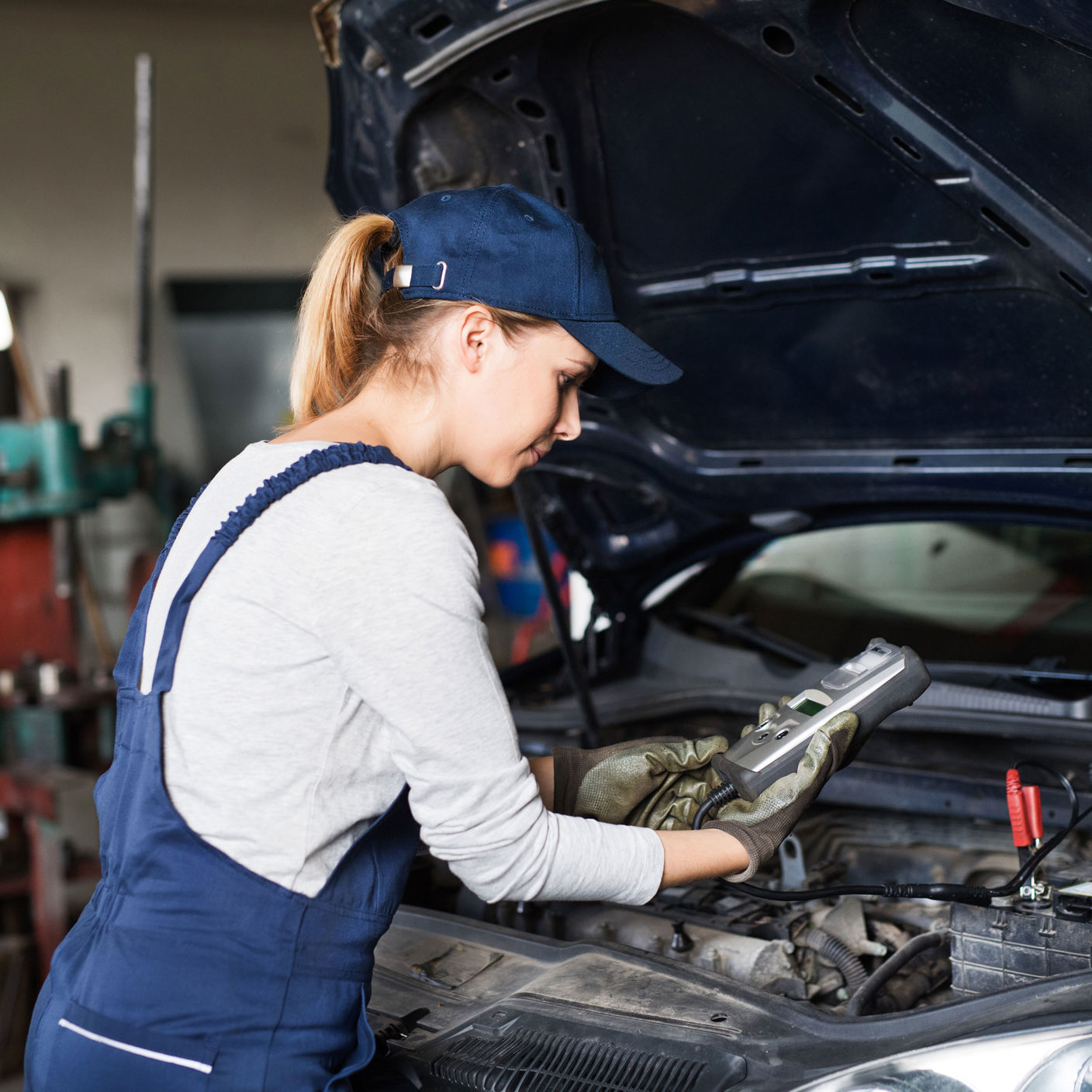Pige i arbejdstøj der roder med biler