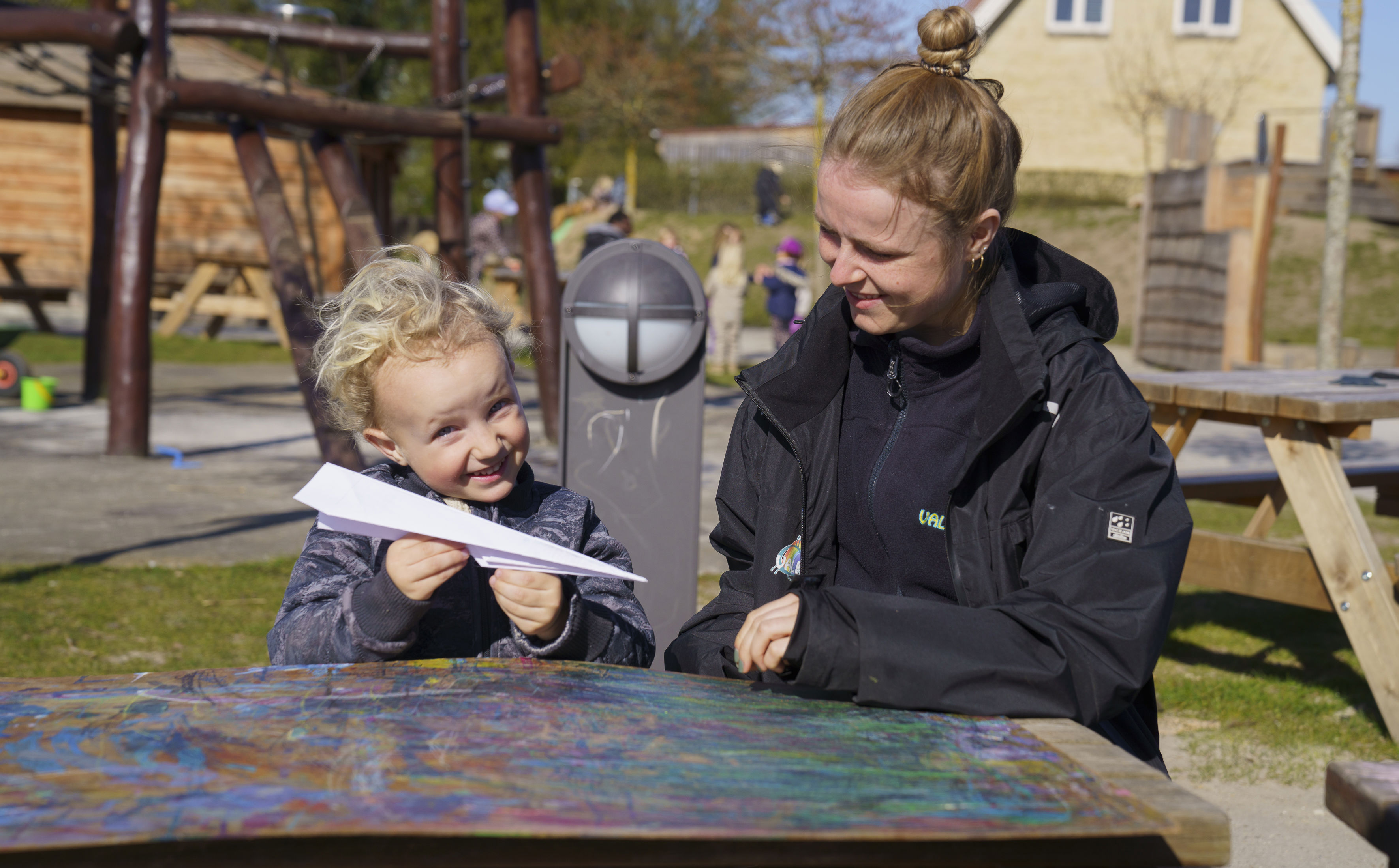 Barn med pædagog og en papirflyver i hånden