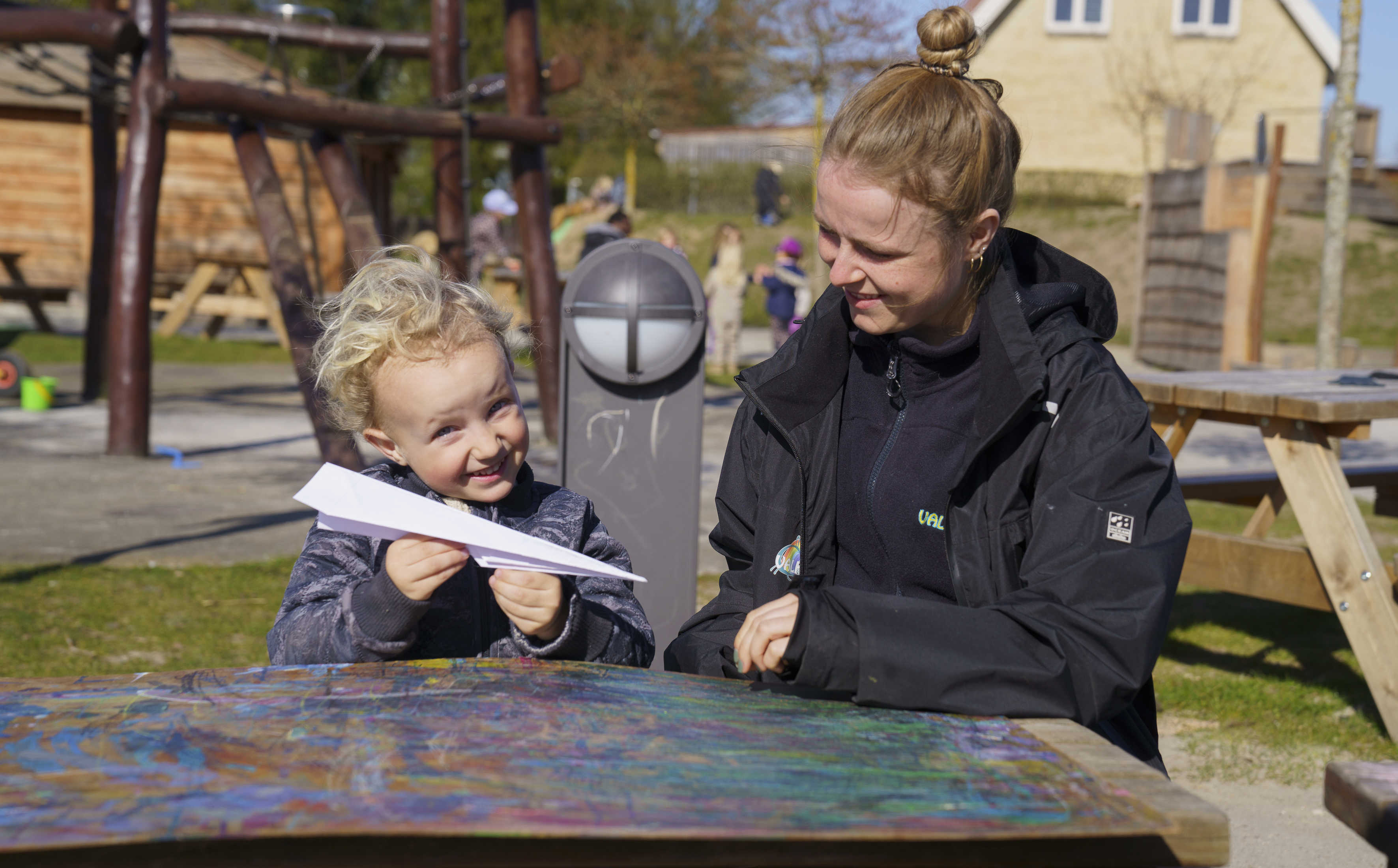 Barn med pædagog og en papirflyver i hånden