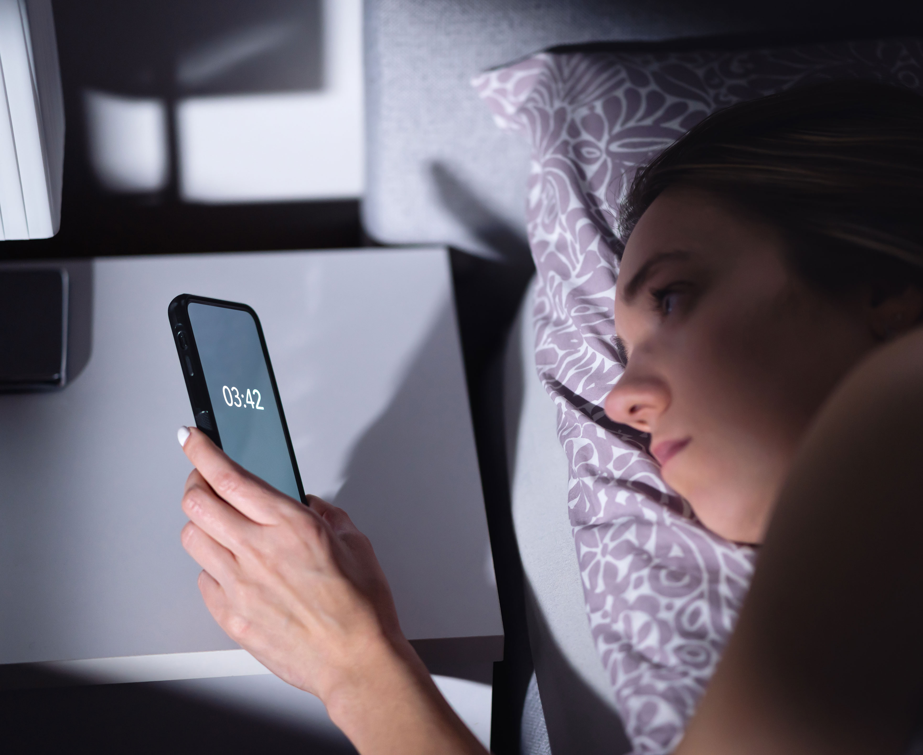 Kvinder der kigger på sin telefon kl 03:42 om natten