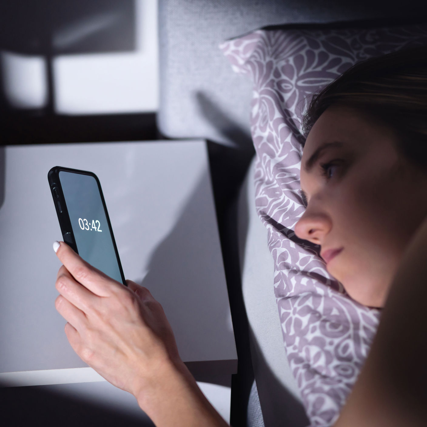 Kvinder der kigger på sin telefon kl 03:42 om natten