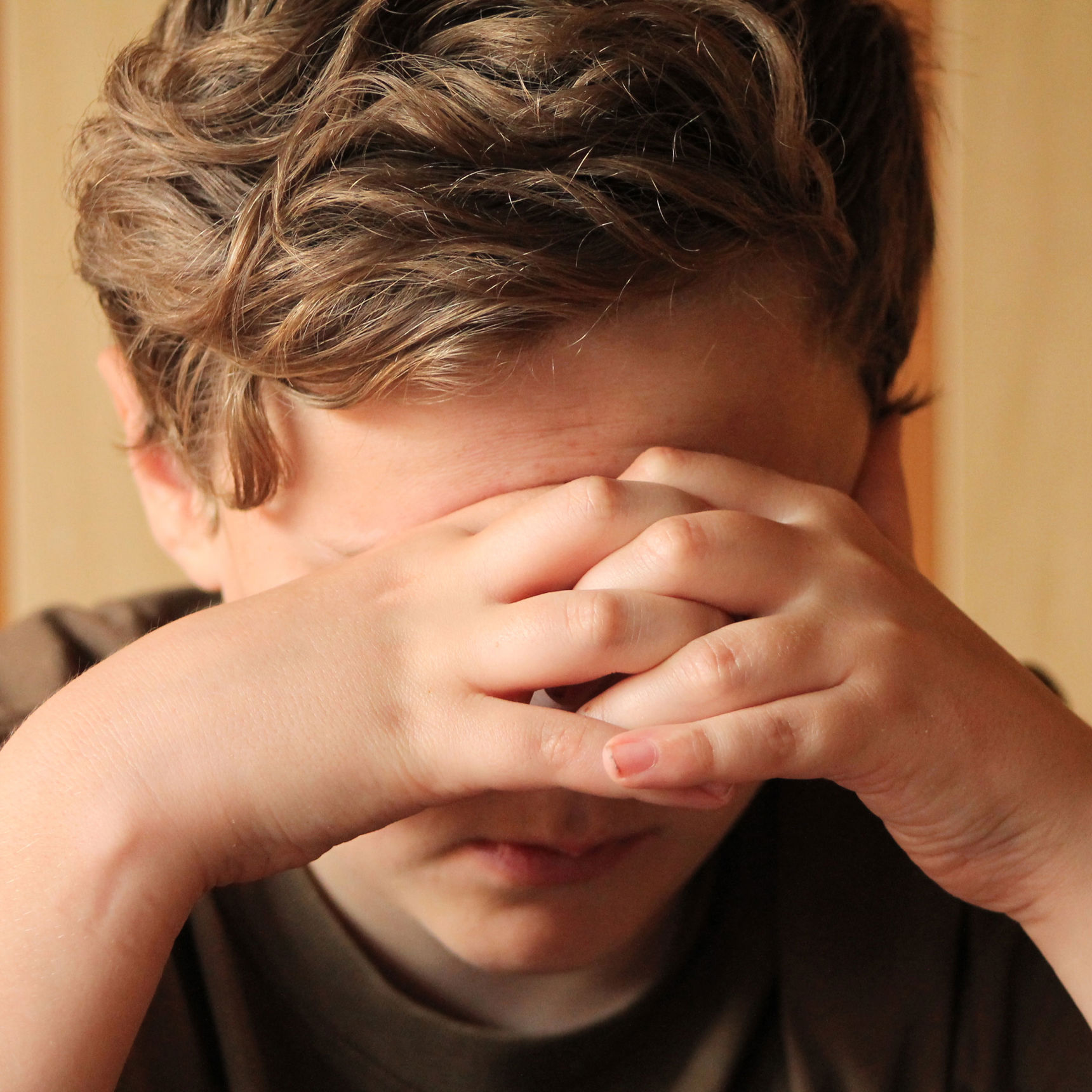 Trist dreng med hænderne for øjnene