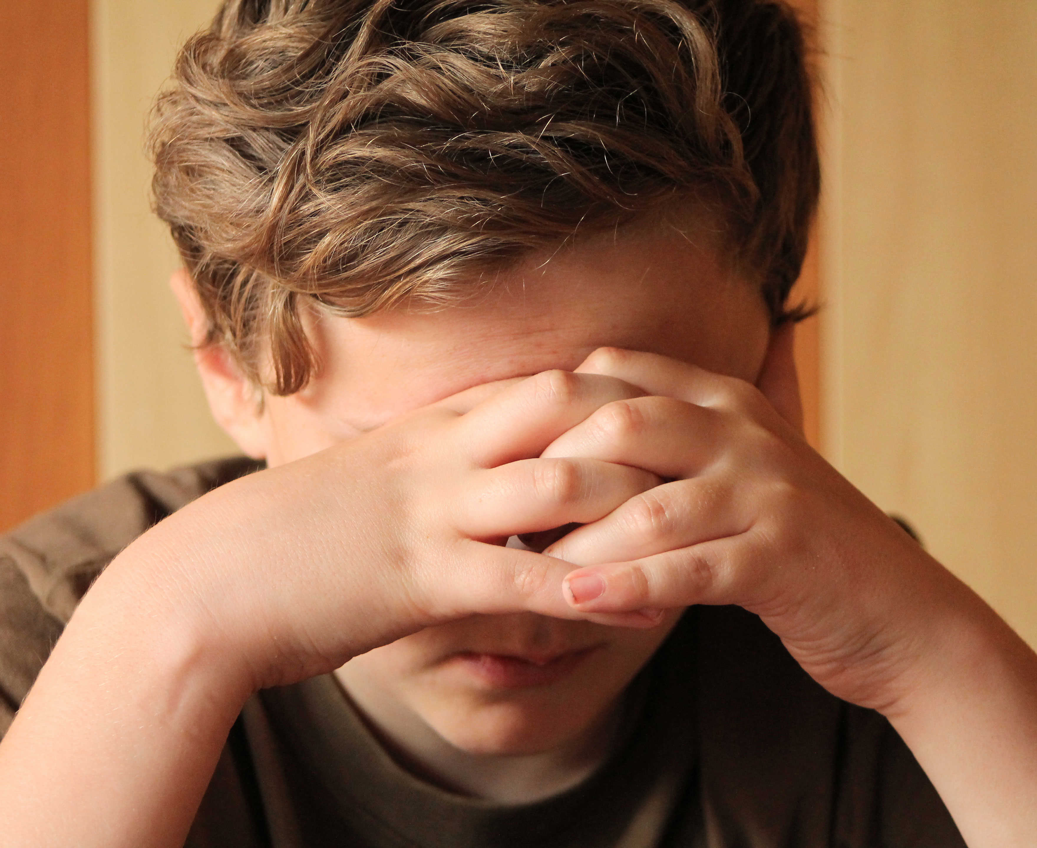 Trist dreng med hænderne for øjnene