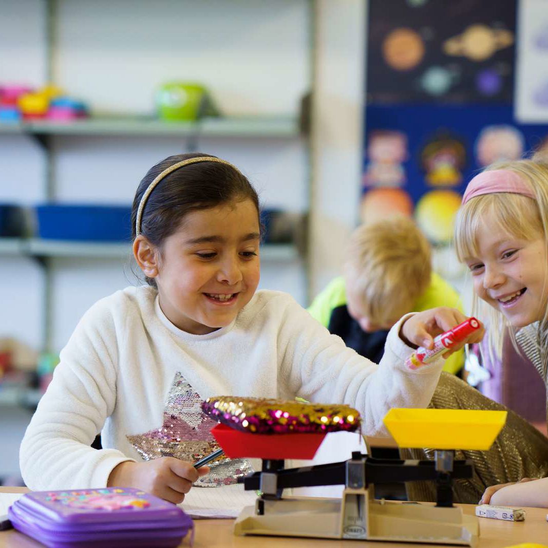 Piger vejer ting i klasselokalet