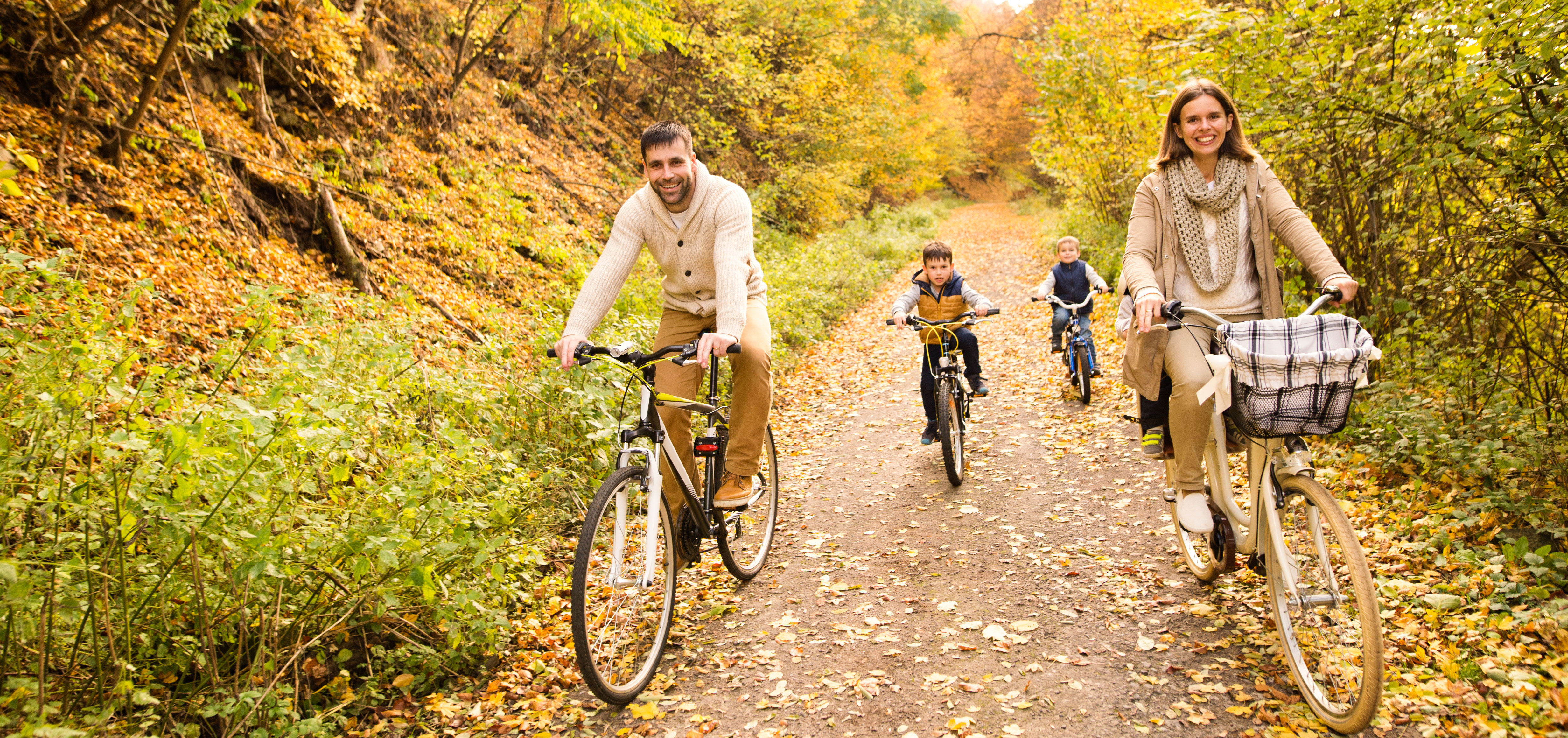 Far, mor og to børn der cykler i skoven