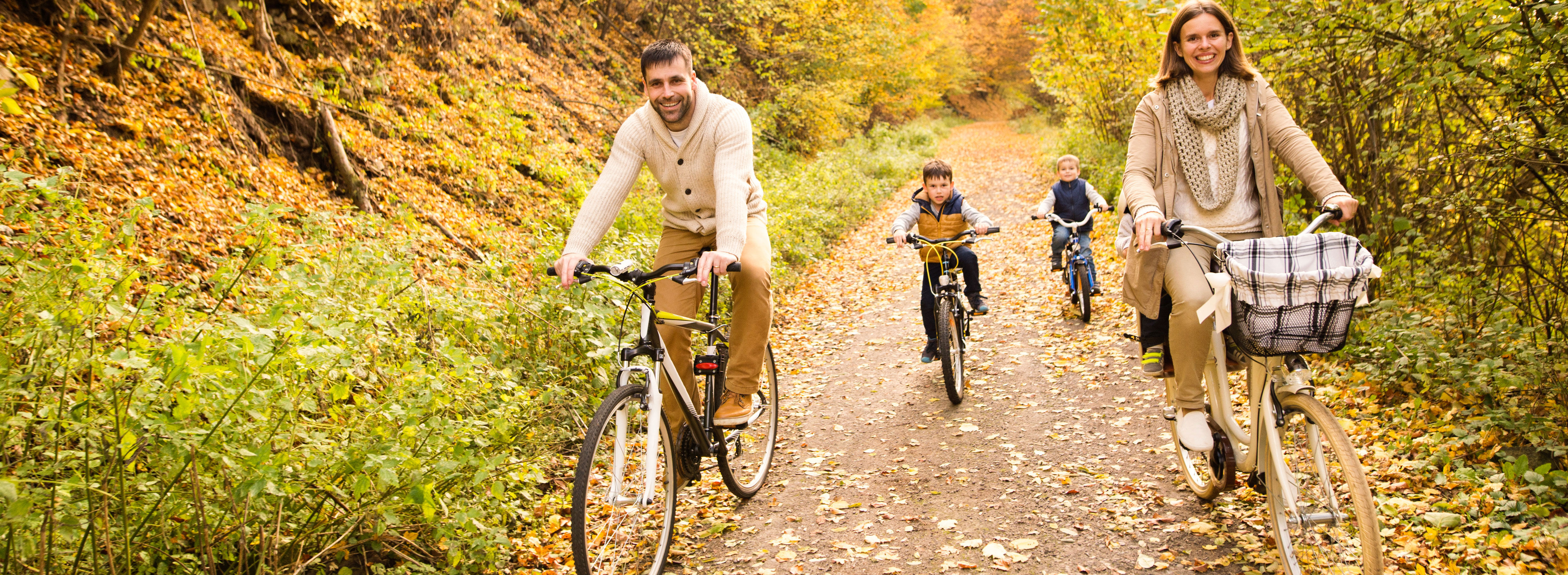 Far, mor og to børn der cykler i skoven