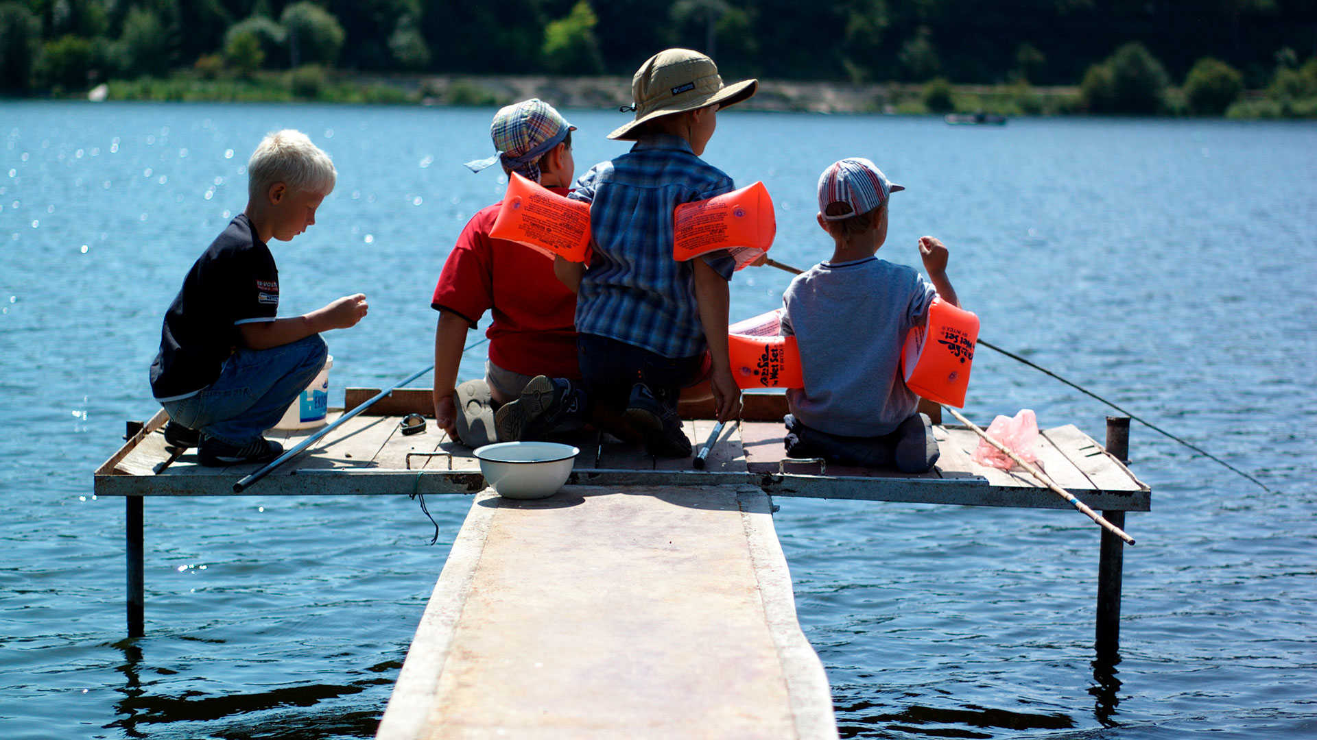 Børn der fisker for enden af en badebro