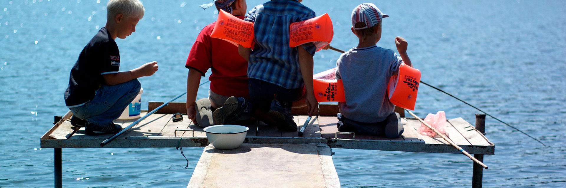 Børn der fisker for enden af en badebro