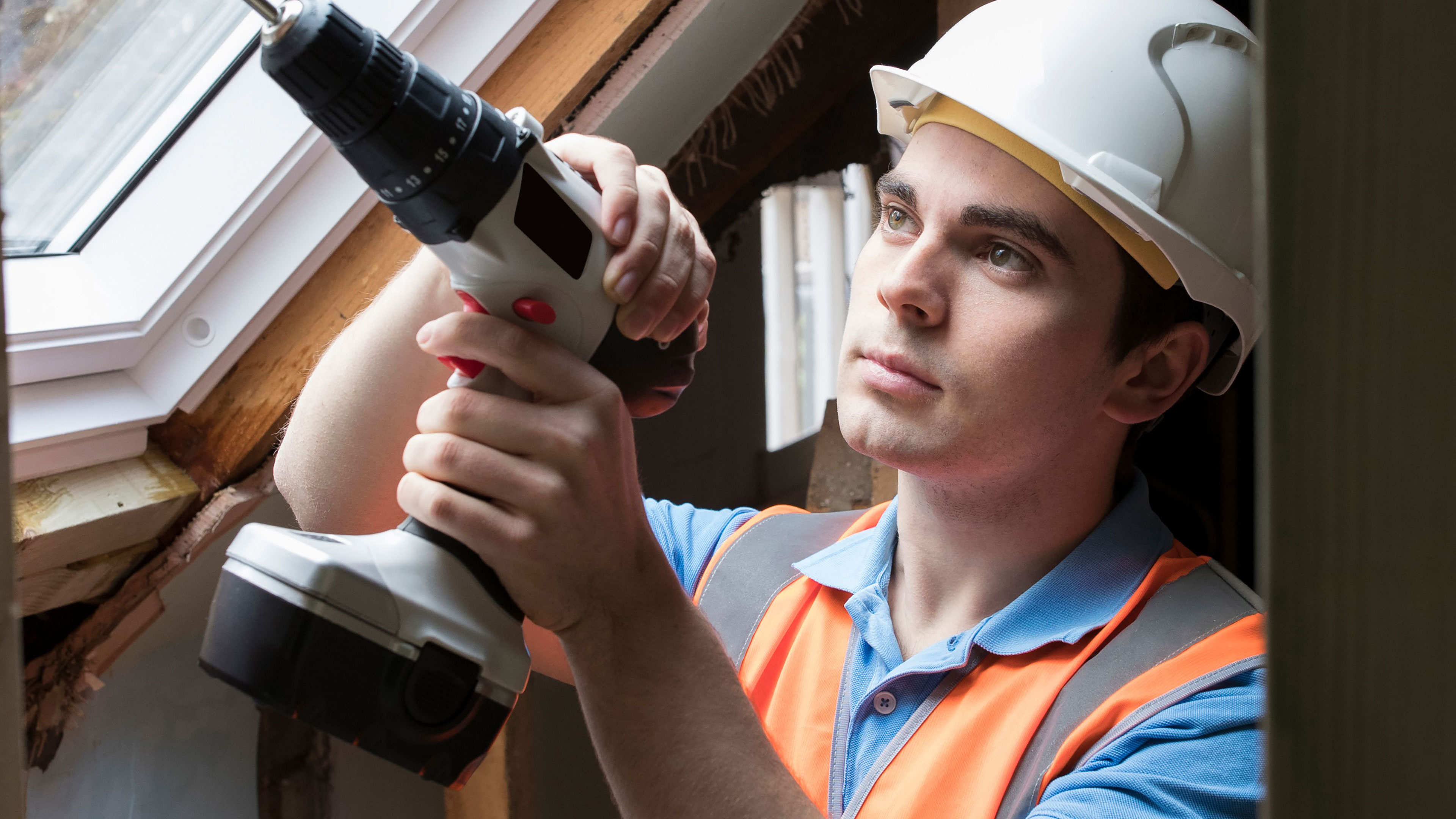 En mand med en skruemaskine og sikkerhedshjelm