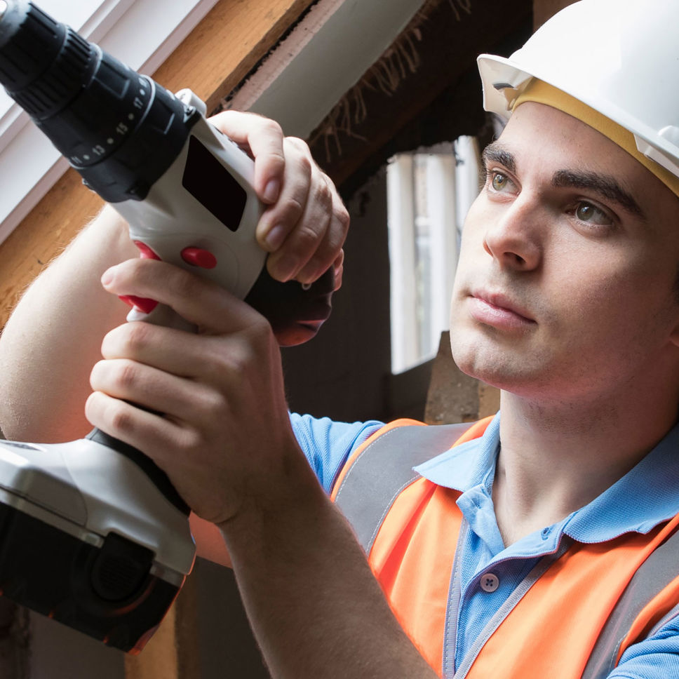 En mand med en skruemaskine og sikkerhedshjelm