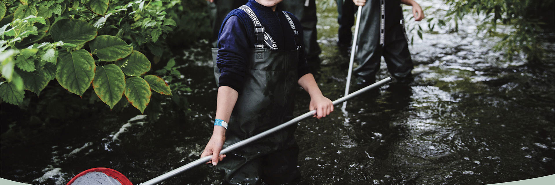 Dreng i vandløb med fiskenet