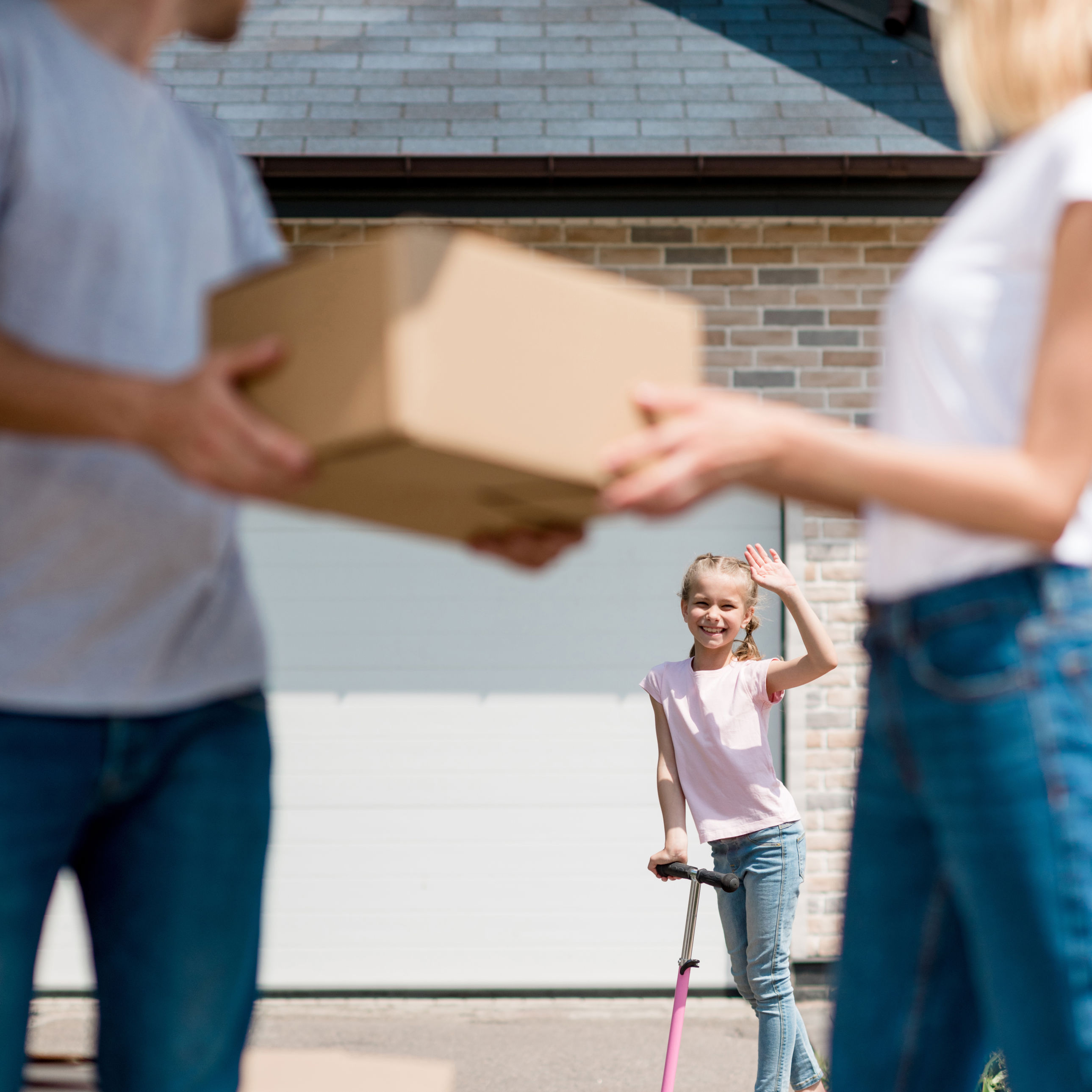 Forældre med en flyttekasse der kigger på deres datter i baggrunden