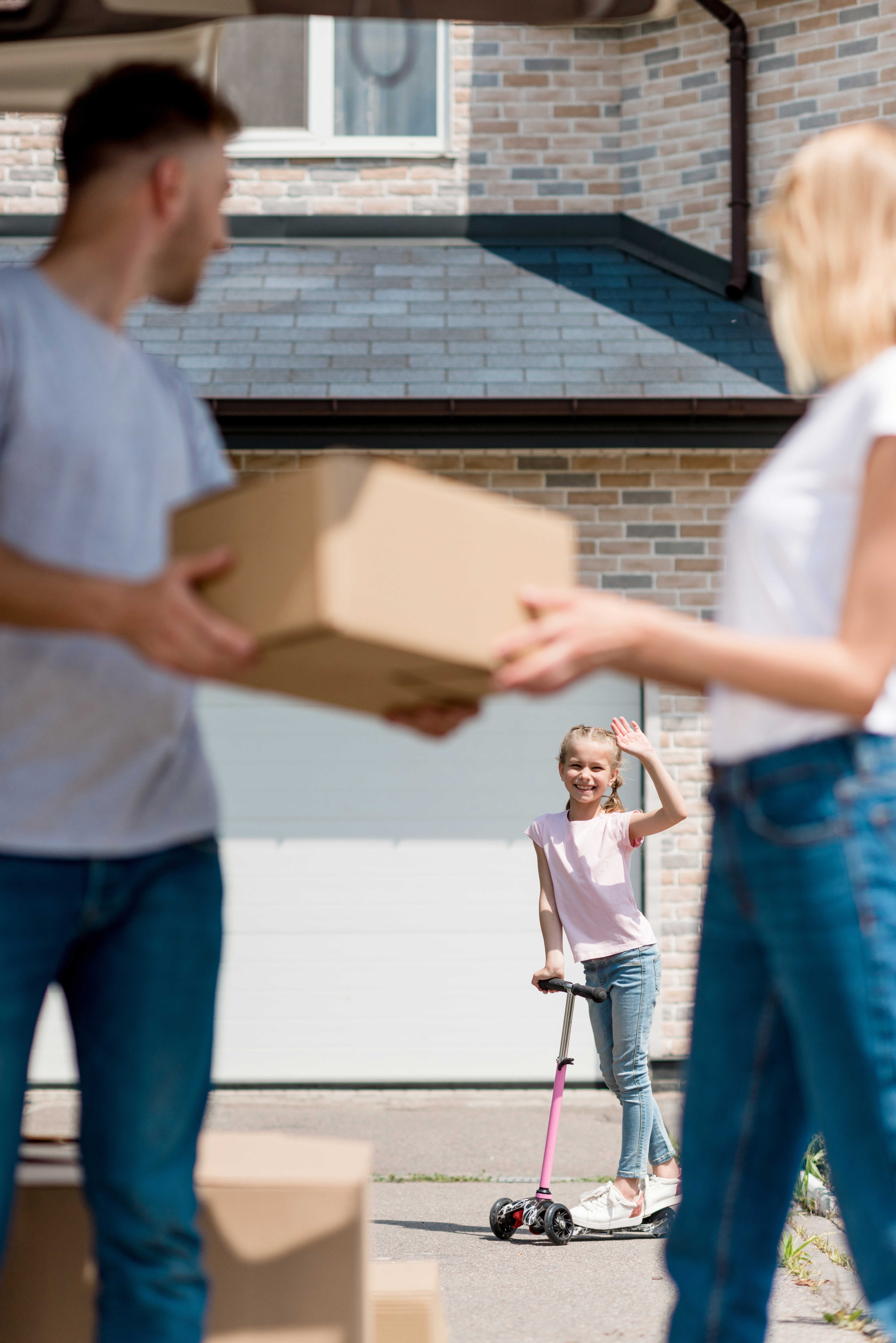 Forældre med en flyttekasse der kigger på deres datter i baggrunden