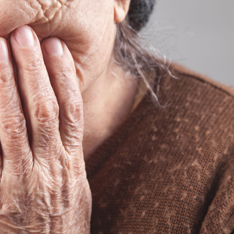 Ældre kvinde tager sig til kinden