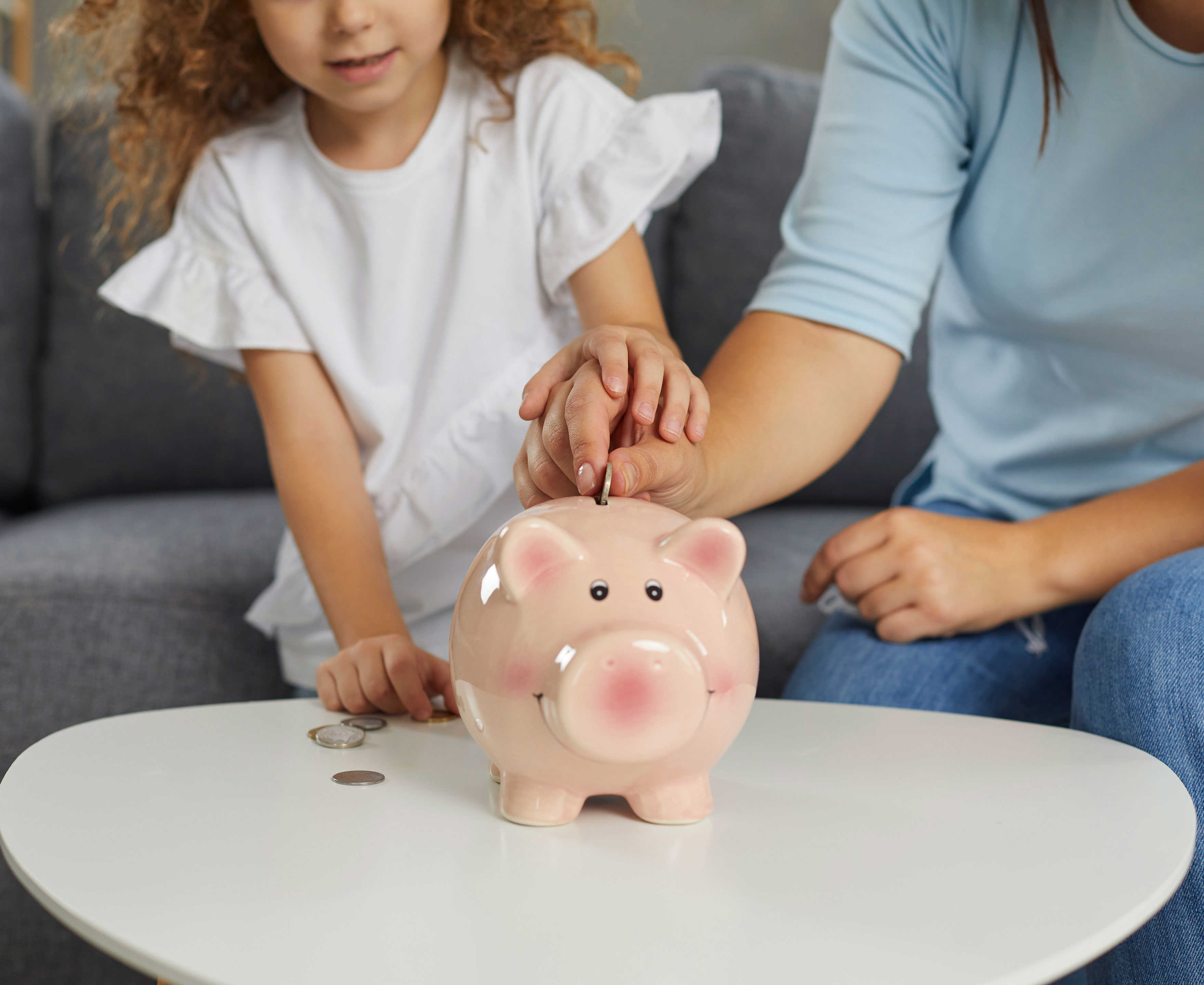 Mor og datter der putter penge i en sparegris