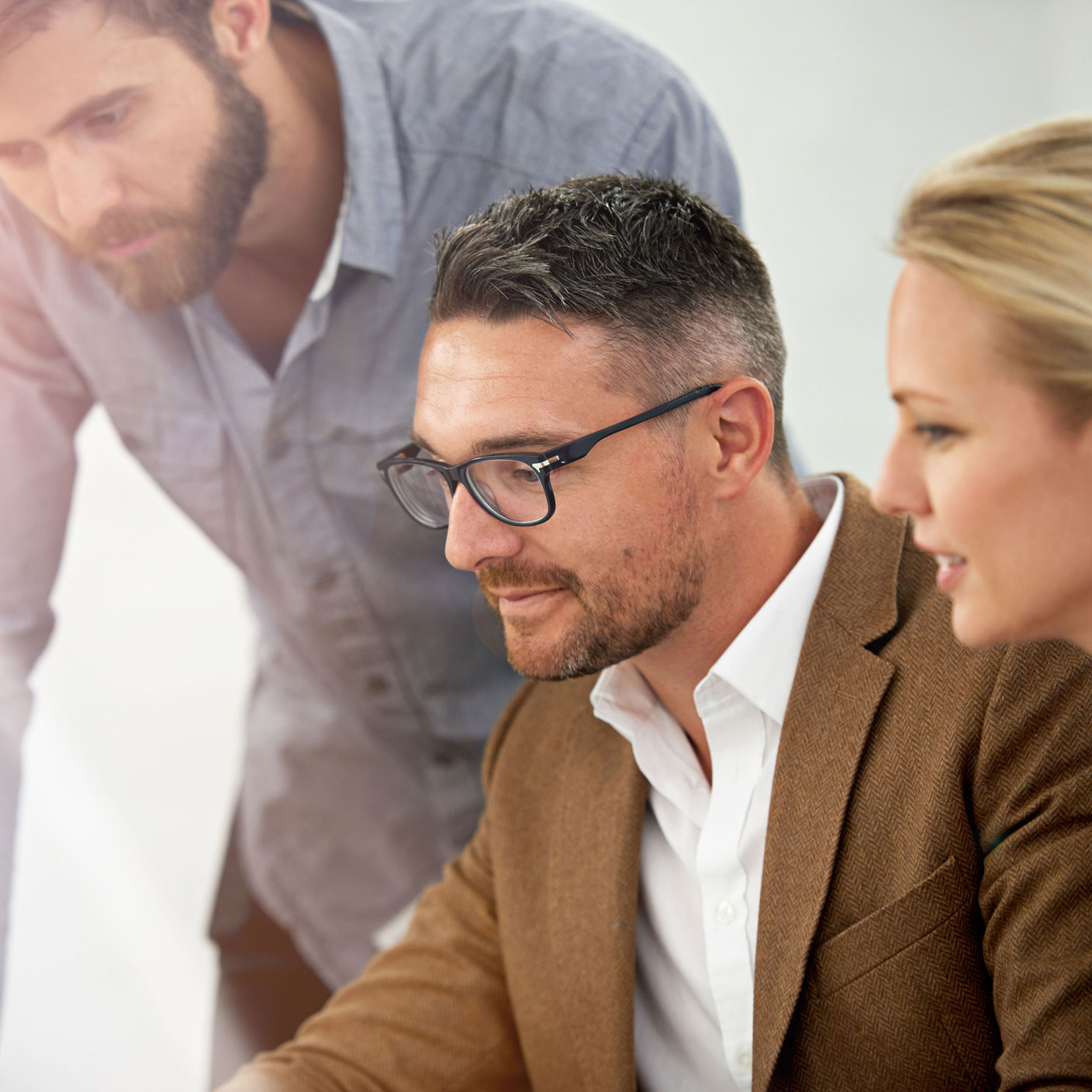 Tre koncentrerede mennesker med blikket rettet mod en PC