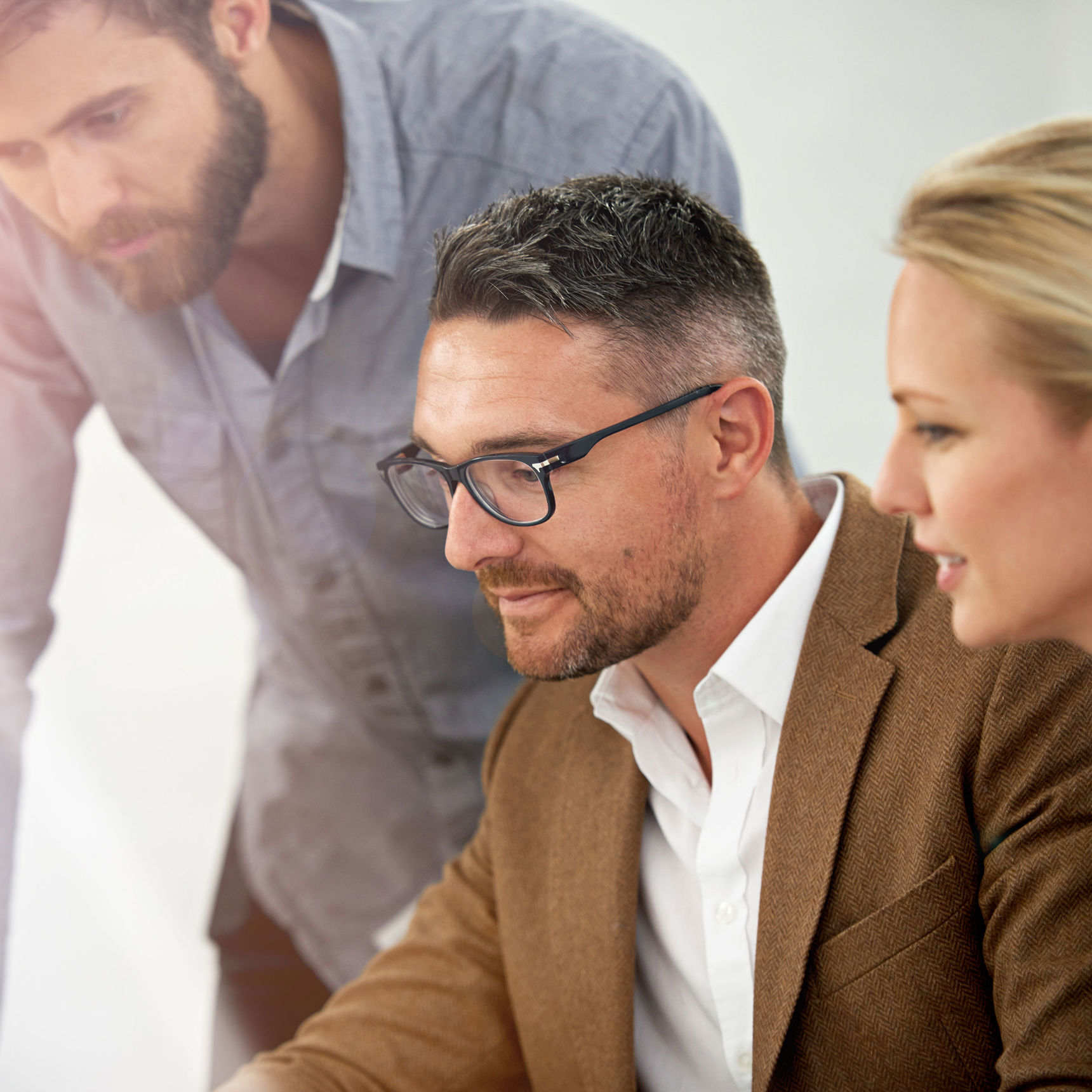 Tre koncentrerede mennesker med blikket rettet mod en PC