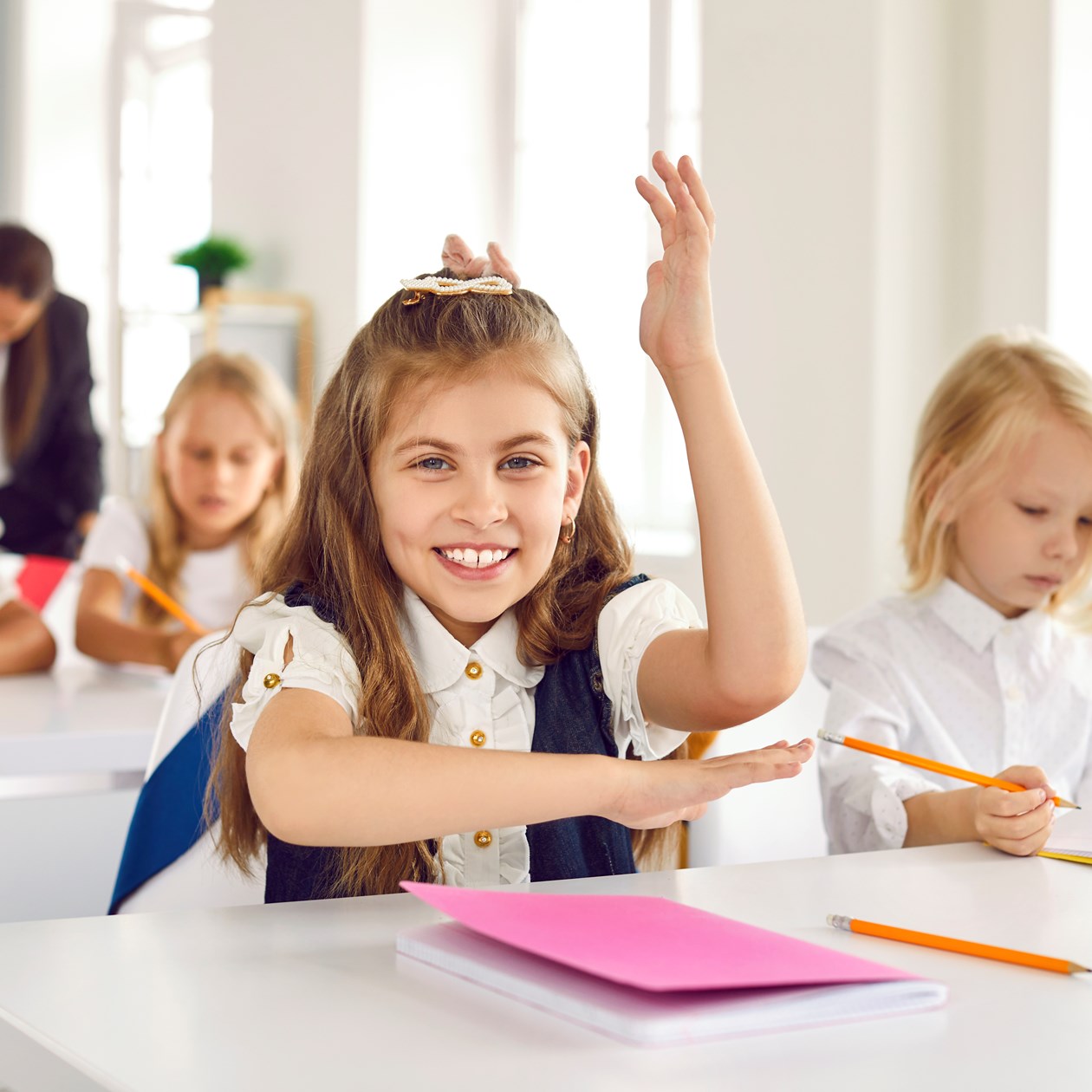 Pige med hånden oppe i klasselokale