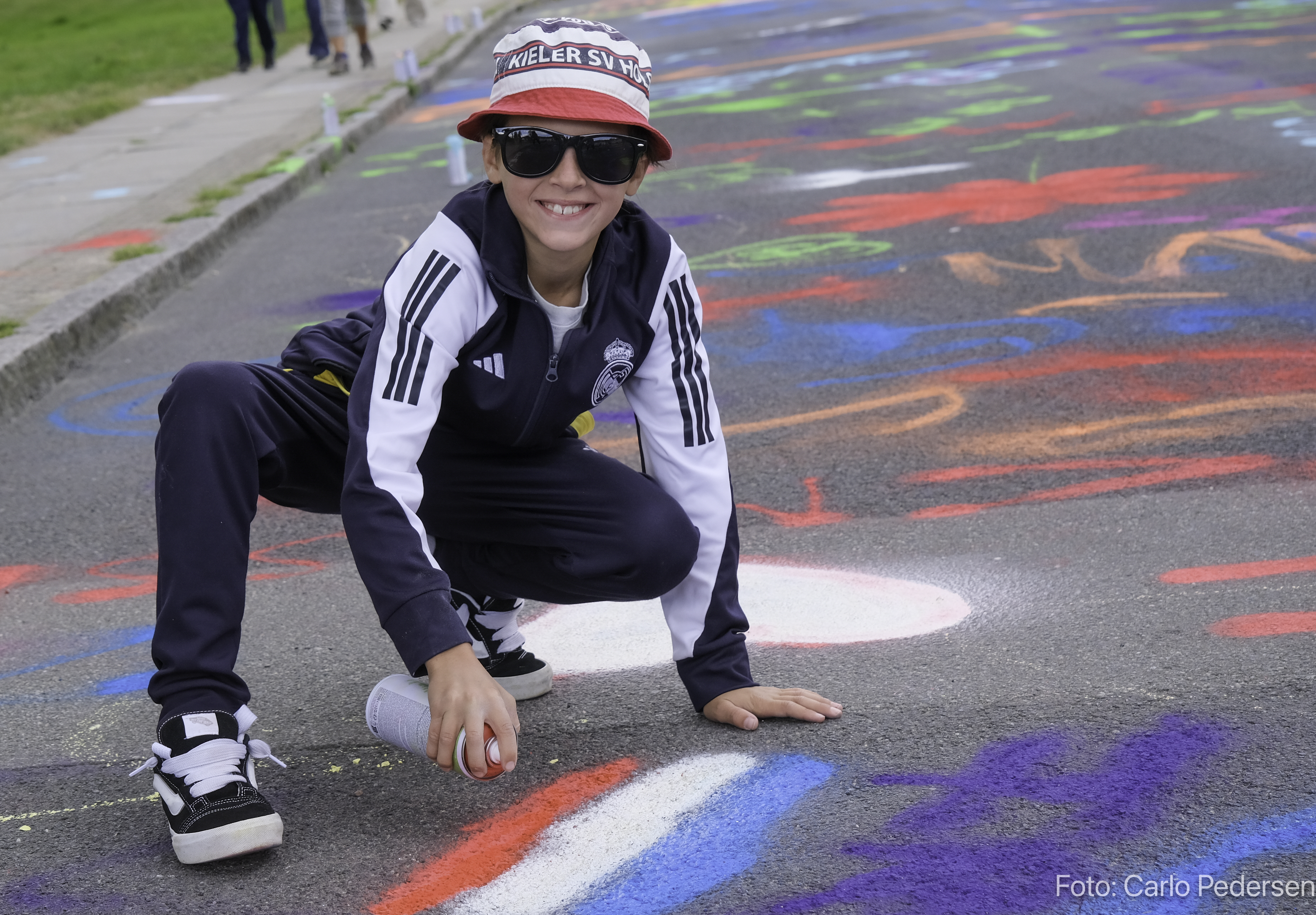 Dreng smiler ved streetart med sprayflaske i hånden