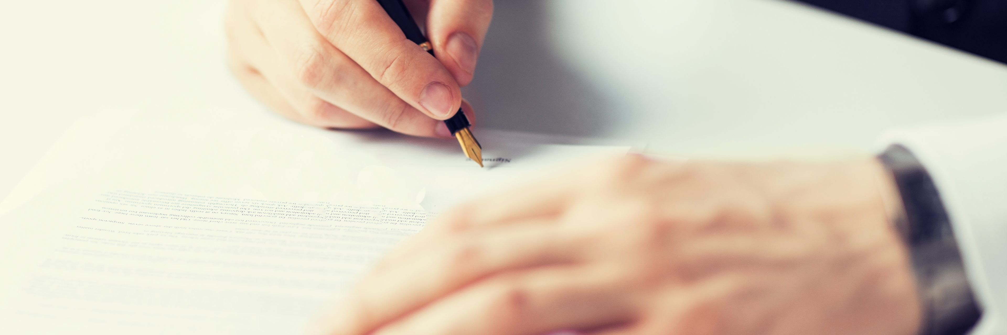 Hånd med kuglepen der underskriver et papir