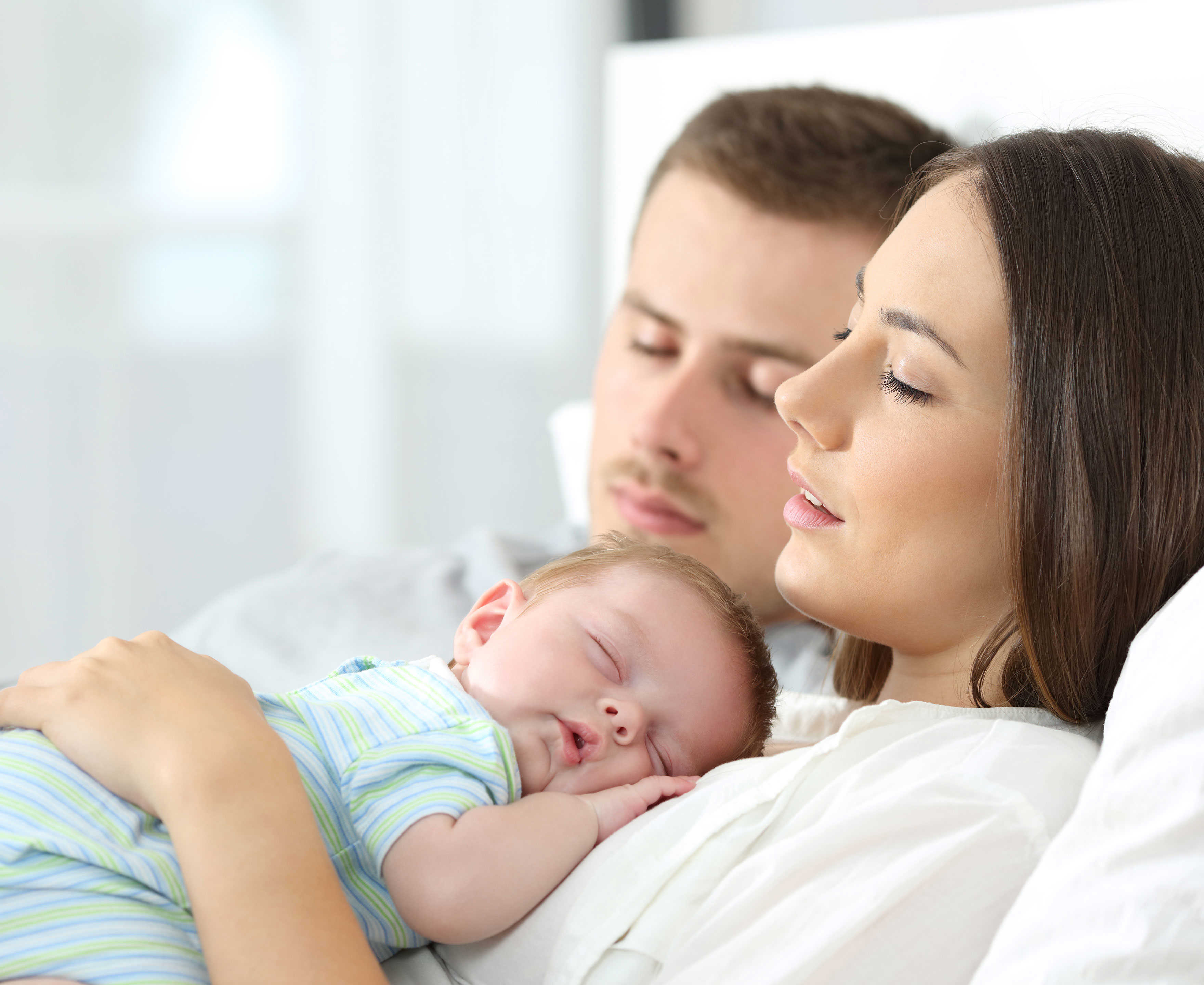 Sovende forældre hvor moren har et sovende spædbarn på maven