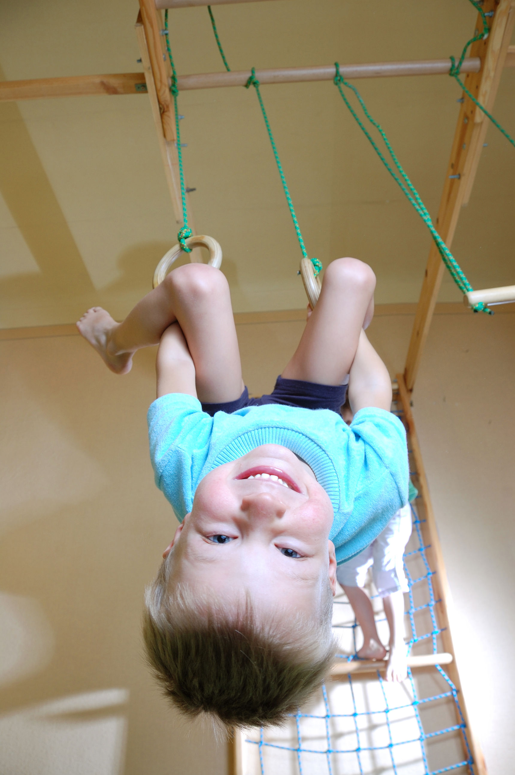 Dreng der sviger sig i ringe i en gymnastiksal