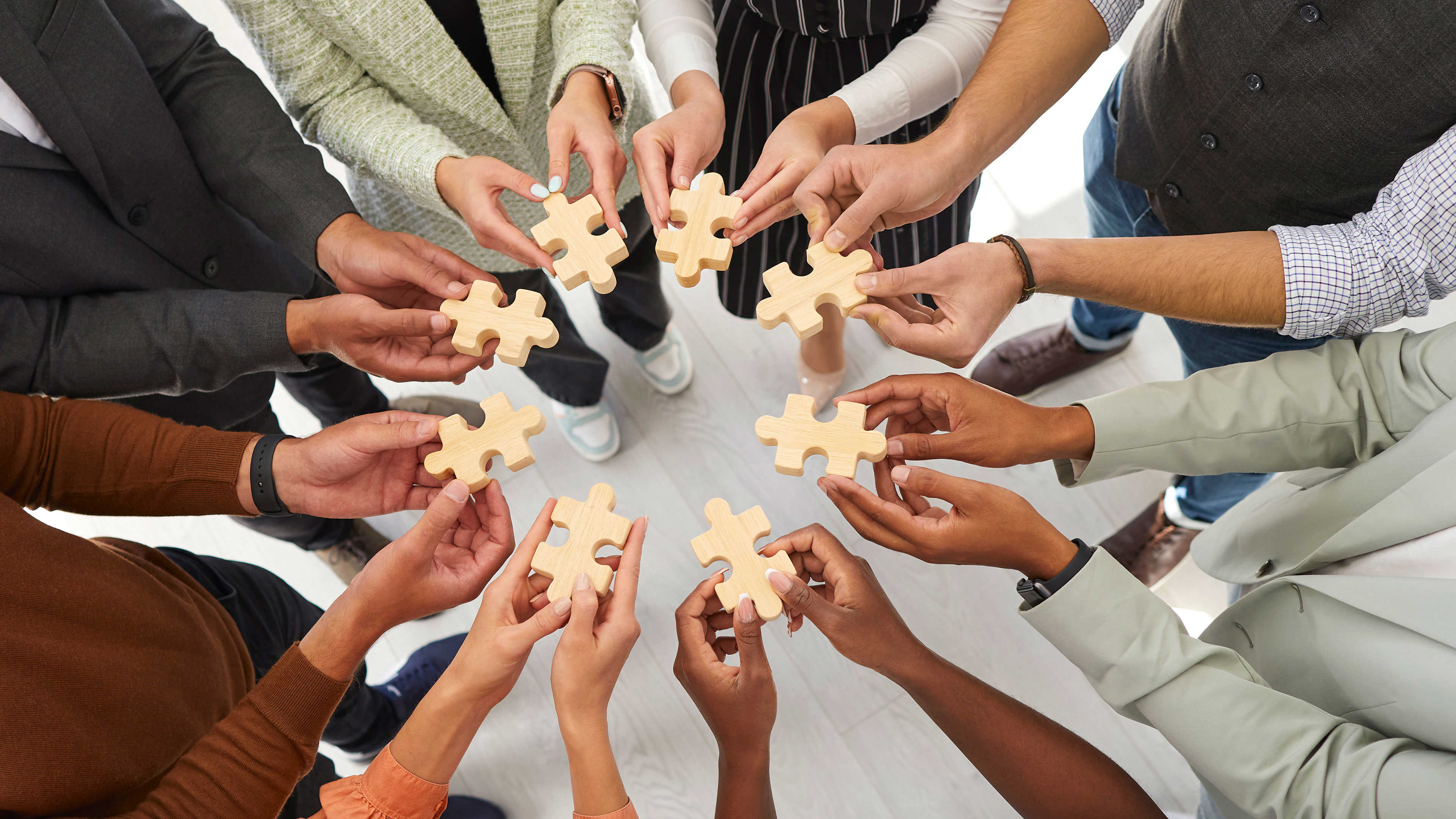 Hænder der hver holder en puslespilsbrik mod hinanden