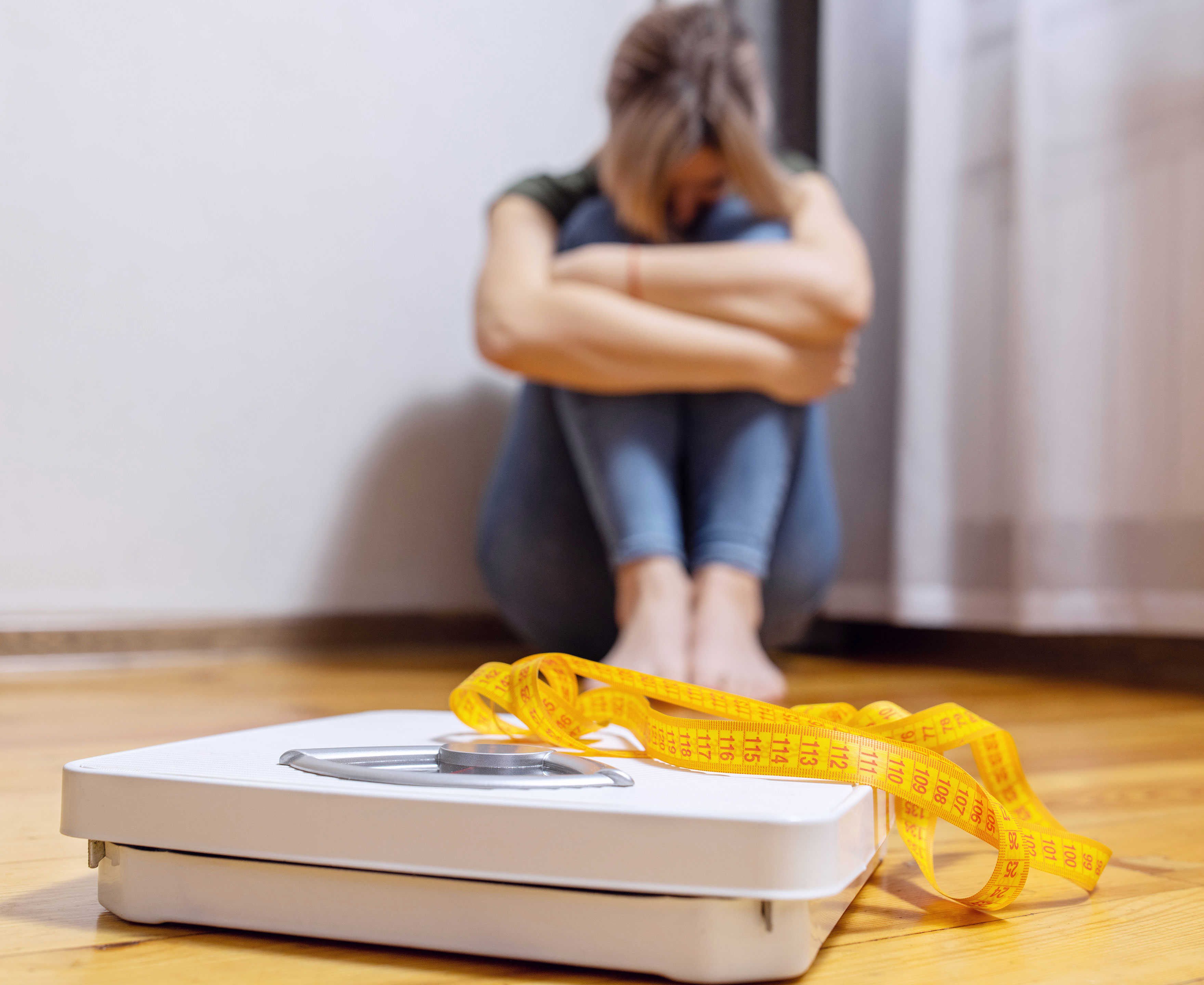 Badevægt med en trist person siddende i baggrunden