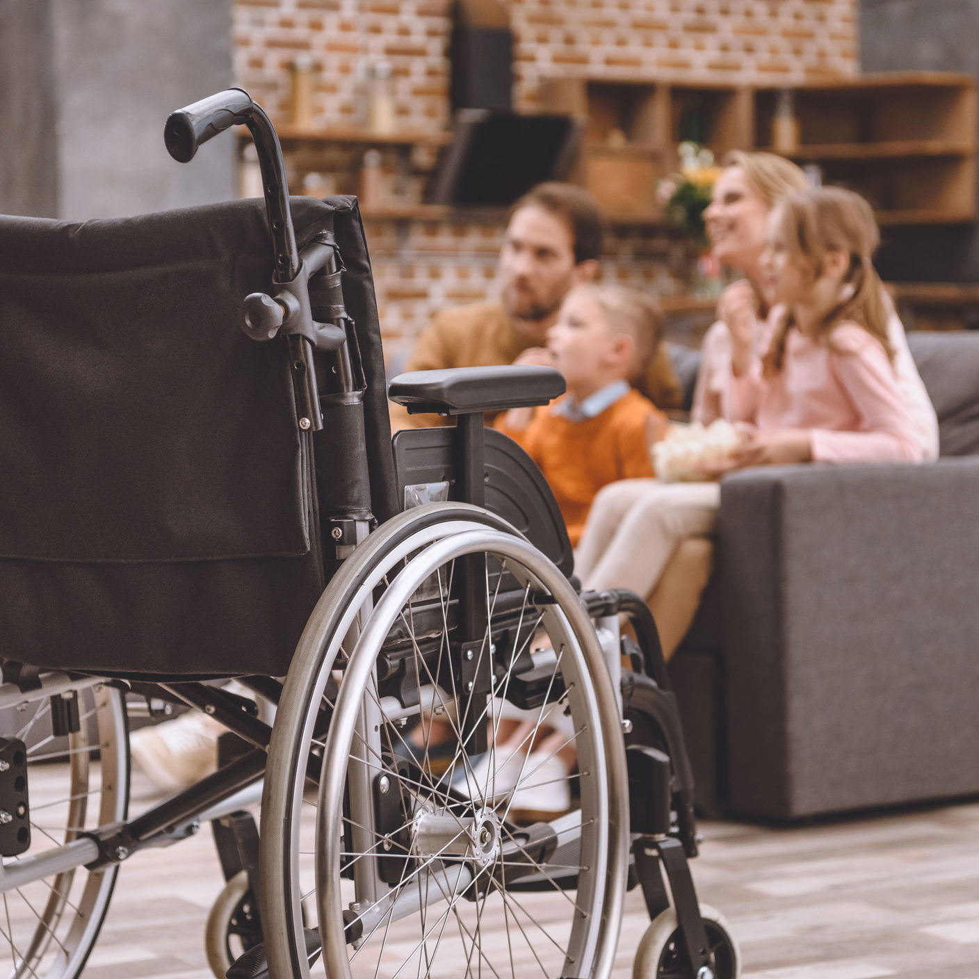 Close up af en kørestol med en familie i baggrunden