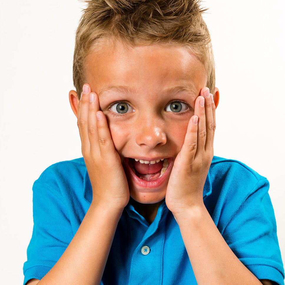 Dreng med åben mund og hænder på kinderne