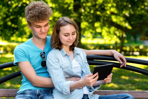 Ungt par på en bænk med en tablet