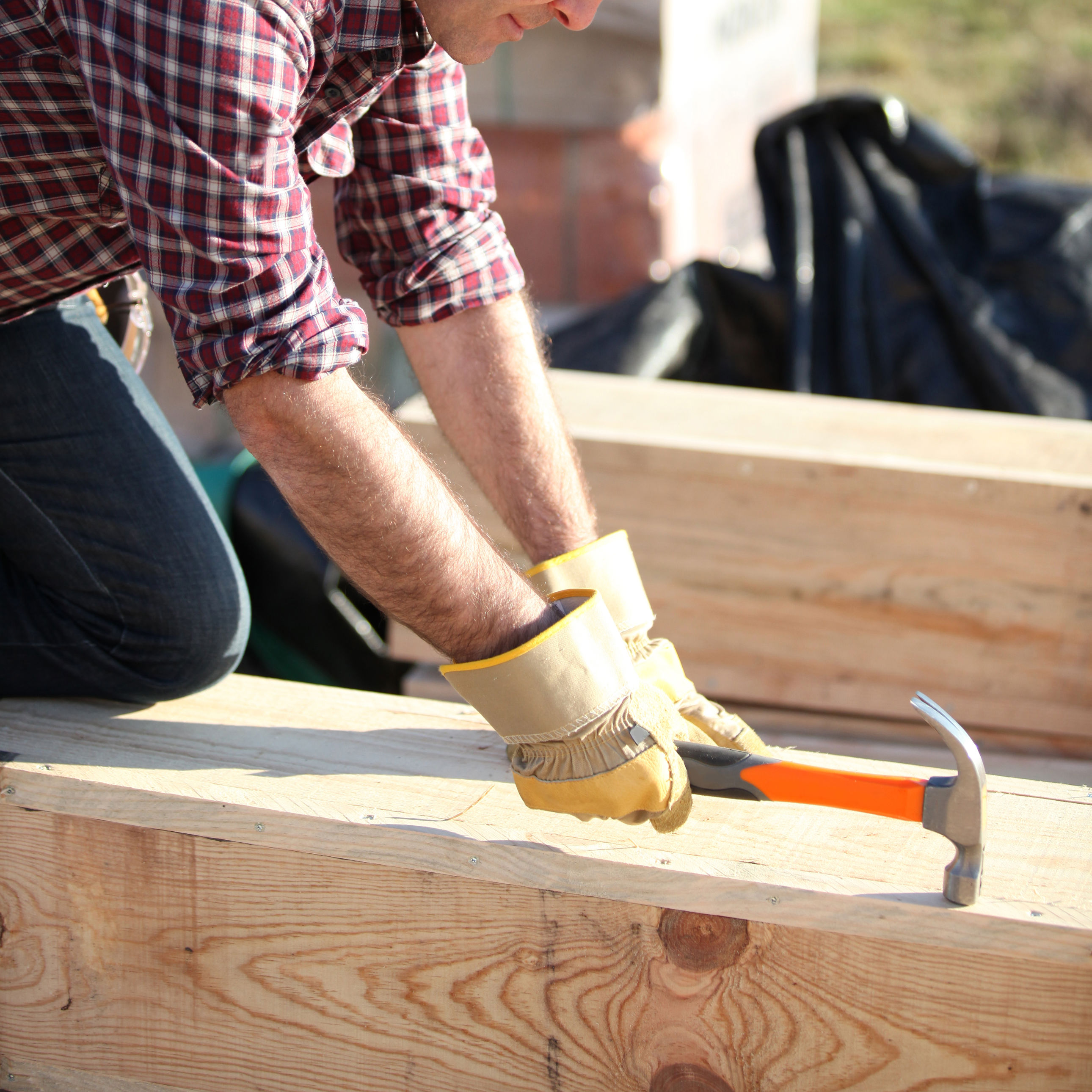 Håndværker slår søm i træ på byggeplads