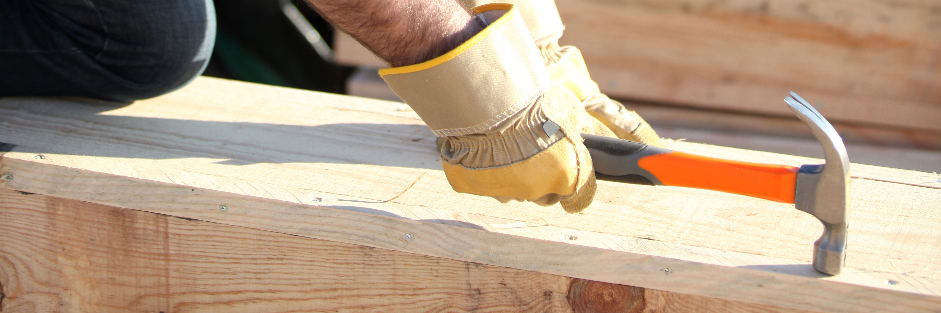 Håndværker slår søm i træ på byggeplads