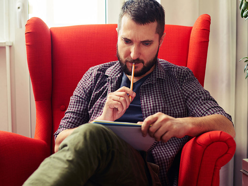Mand i rød lænestol med med blyant og blok